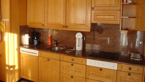Uma cozinha com armários de madeira, uma pia de aço inoxidável e uma máquina de lavar louça embutida.