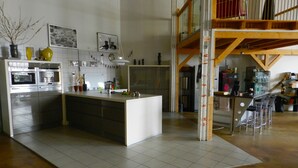 Una cucina moderna con isola centrale, elettrodomestici in acciaio inossidabile e un soppalco con angolo bar.