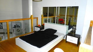 Una camera da letto con un letto, comodini, uno specchio, una finestra e un soffitto in legno.