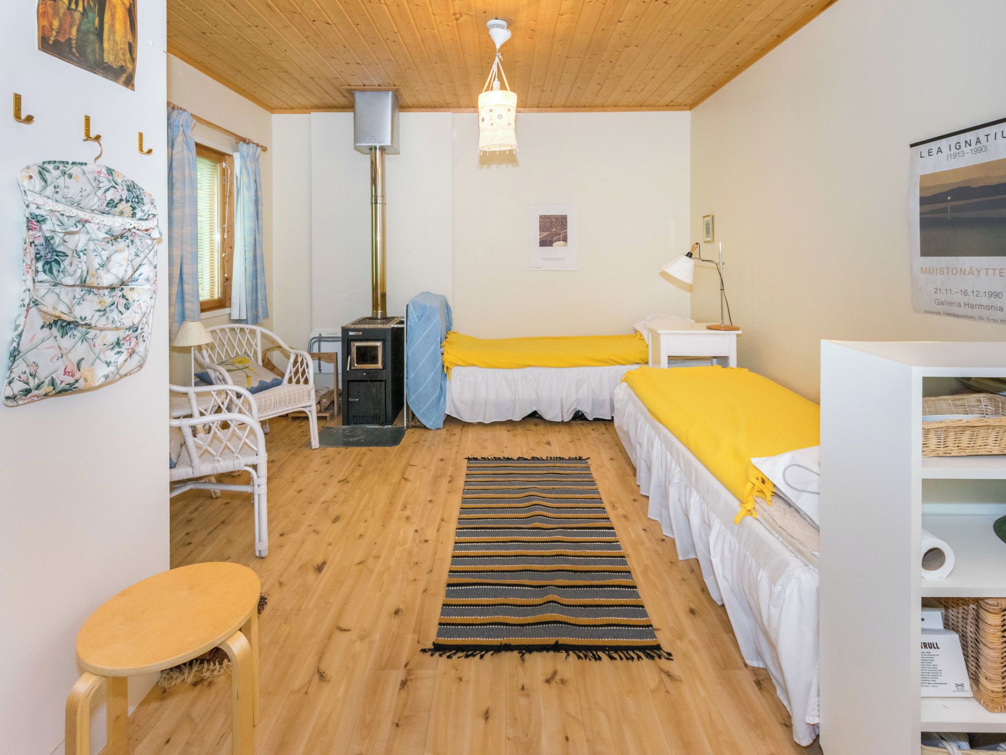 Een gezellige kamer met een bed, een stoel, een klein tafeltje, een verwarming en een hanglamp.
