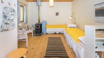 Een gezellige kamer met een bed, een stoel, een klein tafeltje, een verwarming en een hanglamp.