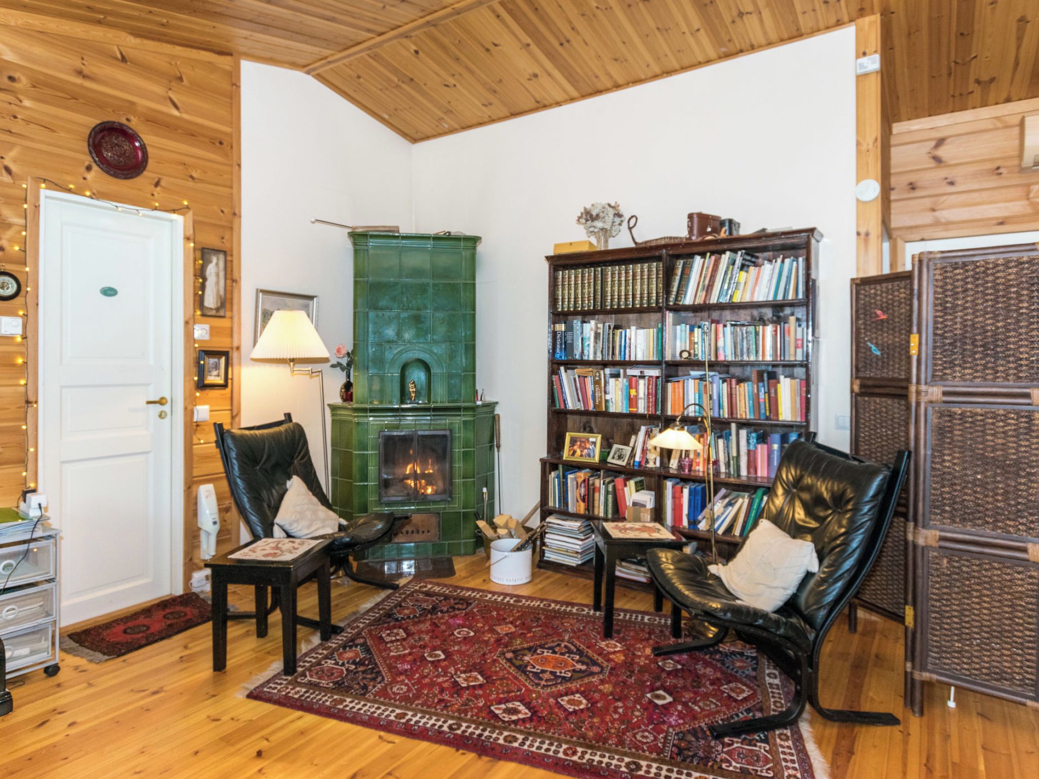 Un salon chaleureux avec une cheminée, des fauteuils en cuir, une bibliothèque et un tapis à motifs.