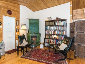 A cozy living room with a fireplace, leather armchairs, a bookshelf, and a patterned rug. - Metsä-iivari by Interhome (Lohja)