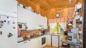 A compact kitchen with white cabinets, a microwave, a coffee maker, and a small refrigerator. - Mets ä-iivari by Interhome (Lohja)