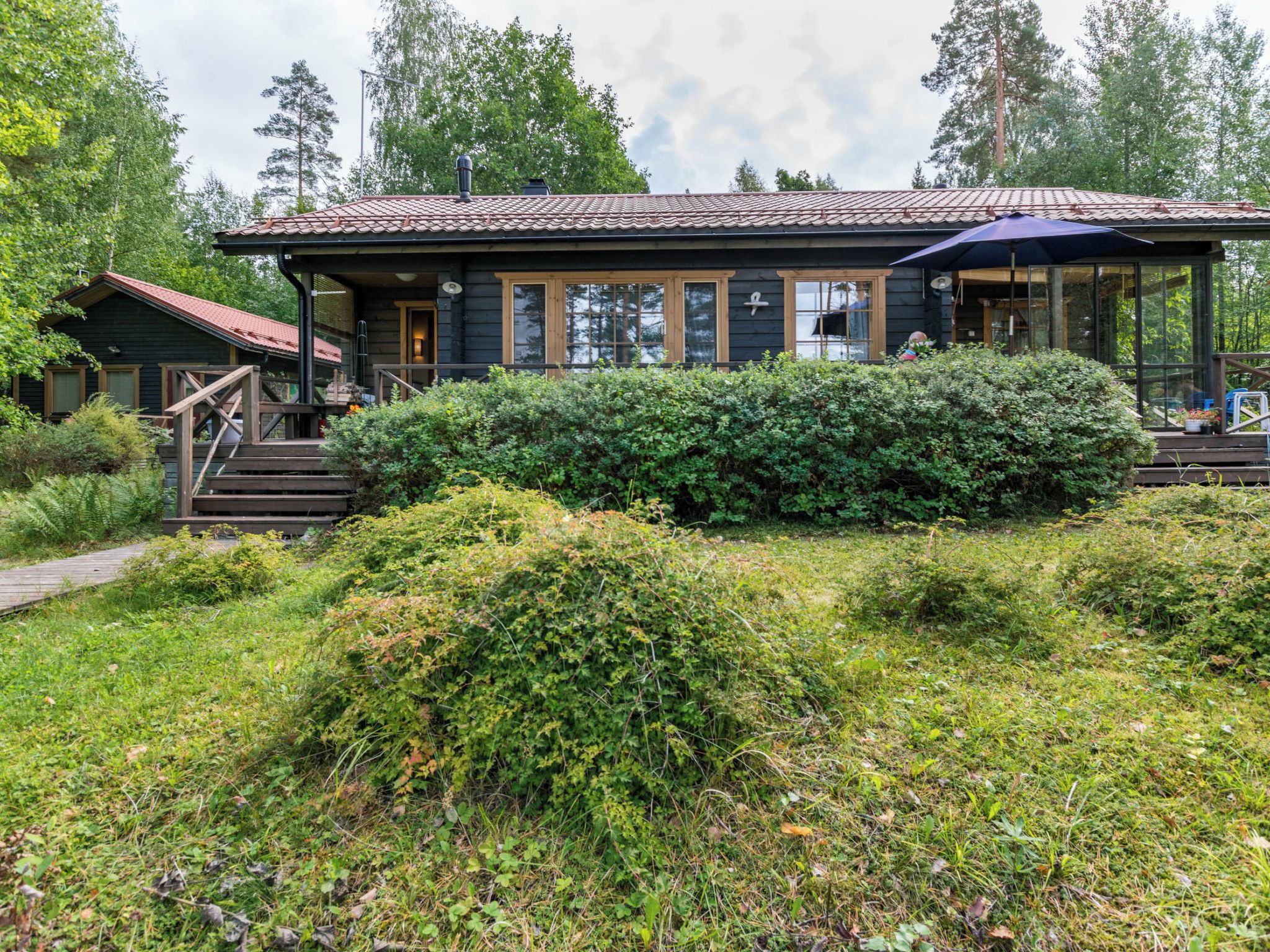 Een chalet met een veranda, een overdekte zithoek buiten en een verzorgde tuin.