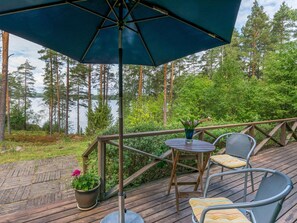 A wooden deck with a table and chairs, a potted plant, and a large umbrella.