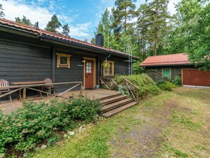A wooden cabin with a porch, a set of stairs leading to the entrance, and a small garden area. - Metsä-iivari by Interhome (Lohja)