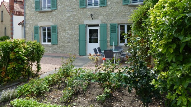 A stone house with green shutters, a door, and a small outdoor seating area with chairs. - Charming cottage in Saint-Bonnet-de-Rochefort with private garden (Saint-Bonnet-de-Rochefort)