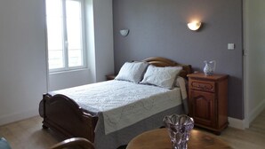 A bedroom with a bed, a nightstand, a lamp, and a window. - Charming cottage in Saint-Bonnet-de-Rochefort with private garden (Saint-Bonnet-de-Rochefort)