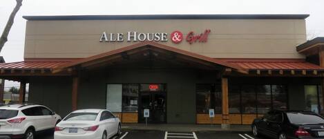 Un edificio con un cartello che riporta la scritta "ALE HOUSE & Grill" e un parcheggio con posti riservati ai disabili.