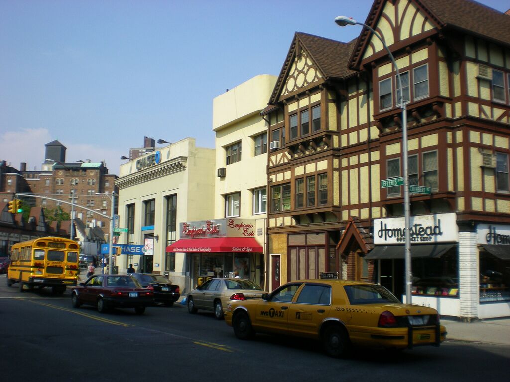 A street view with a yellow school bus, a yellow taxi, and various storefronts including Chase, Emporio Armani, and Homehead.