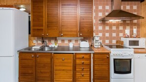 A compact kitchen with wooden cabinets, a stainless steel countertop, a built-in oven, and a microwave. - Vacation home Pöllö by Interhome (Kouvola)