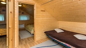A wooden cabin with a loft bedroom, a small bathroom, and a sleeping area with a bed and pillows. - Vacation home Pöllö by Interhome (Kouvola)