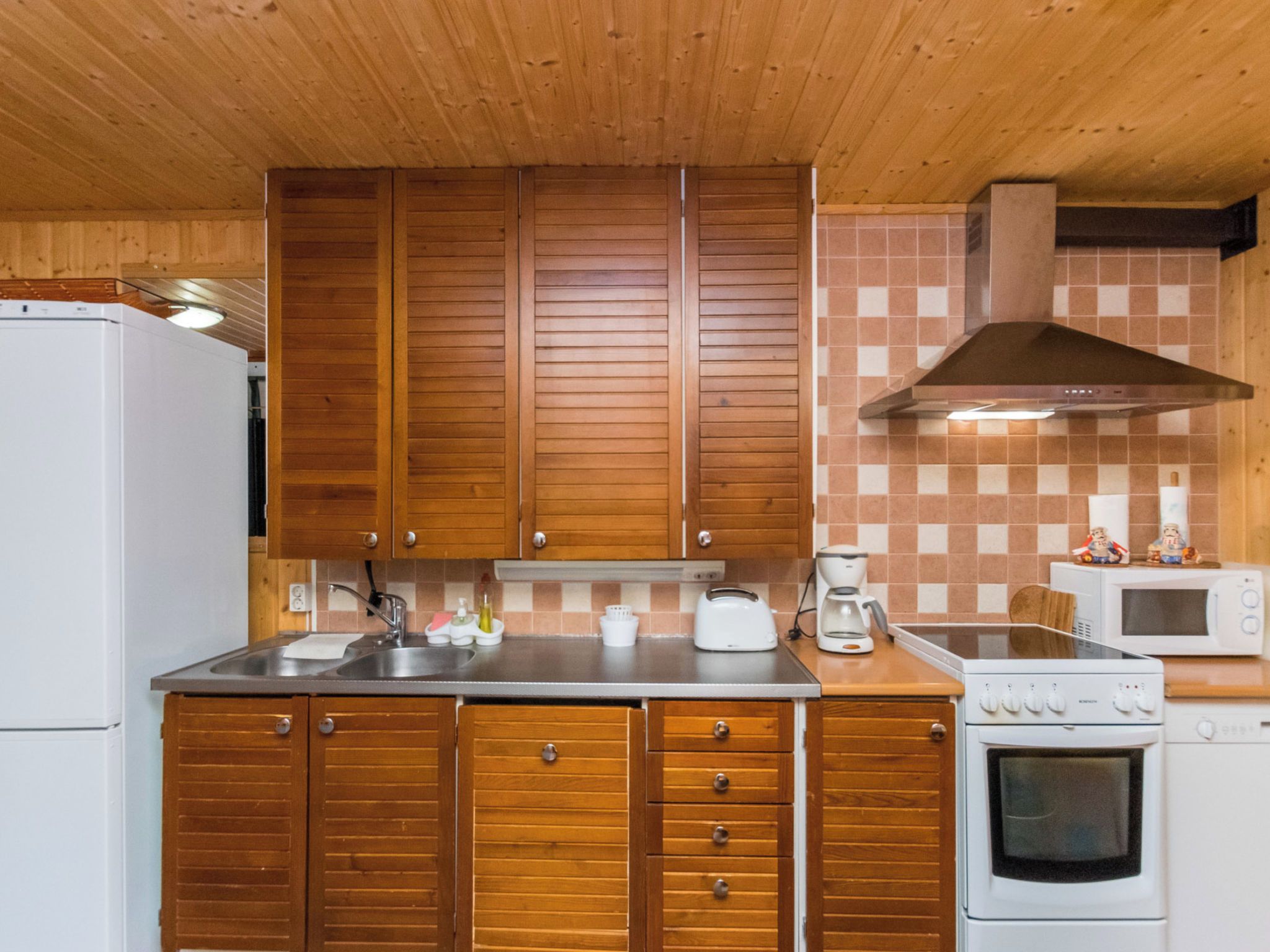 A kitchen with wooden cabinets, a stainless steel sink, a toaster, a coffee maker, a microwave, and an oven.