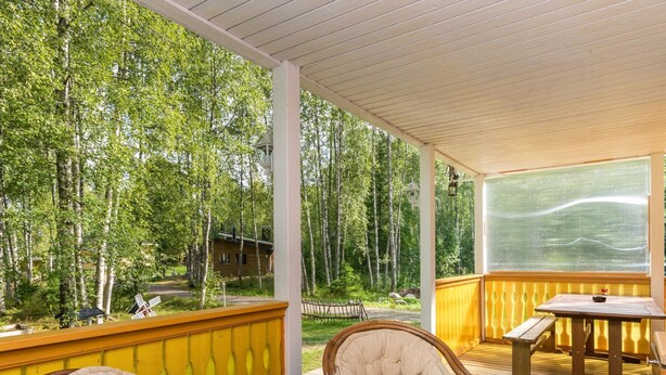 A covered outdoor deck with wooden chairs and a table, overlooking a forested area. - Vacation home Pöllö by Interhome (Kouvola)