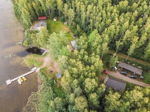 An aerial view of a lakeside property with multiple cabins, a dock with boats, and dense surrounding forest. - Vacation home Pöllö by Interhome (Kouvola)
