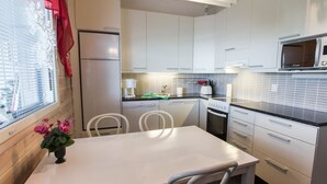 A compact kitchen with white cabinets, a microwave, a dishwasher, and a window with blinds.