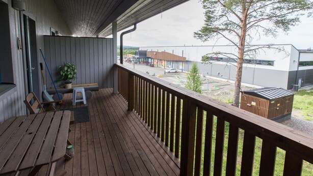 A wooden deck with a view of a parking lot and buildings.