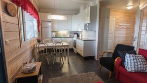 A compact kitchen with white cabinets, a microwave, and a dining area with a table and chairs.