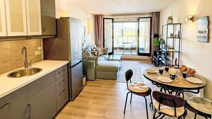 Una cuina moderna amb un rentatge, armaris i zona de menjador amb taula i cadires.
