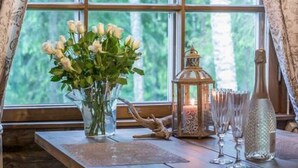 A room with a large window, a vase with flowers, a lantern, and a bottle on a wooden table. - Mäkitorppa by Interhome (Asikkala)