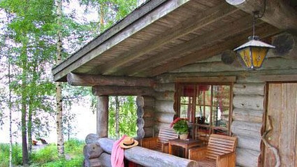 A rustic log cabin with a porch, wooden furniture, and a hanging lantern. - Mäkitorppa by Interhome (Asikkala)