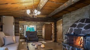 A cozy log cabin interior with a stone fireplace, wooden beams, and a comfortable seating area. - Mäkitorppa by Interhome (Asikkala)