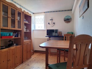 A kitchen with wooden cabinets, a dining table, and chairs.