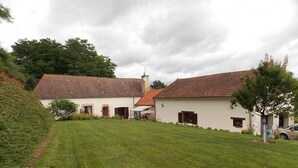 A rural property with two white buildings, a grassy yard, and a car parked nearby.