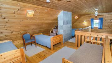 A wooden cabin with a loft bedroom, a small seating area, and a staircase.