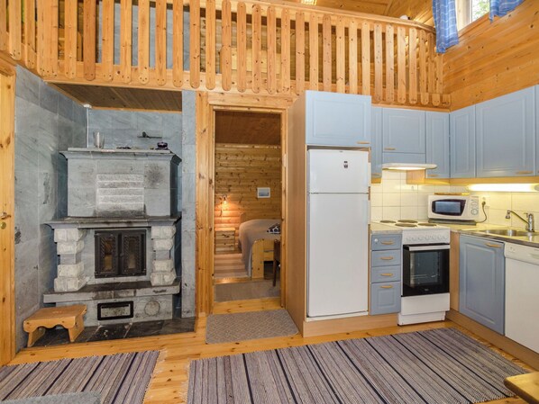 A compact kitchen with a stone fireplace, a refrigerator, and a microwave.