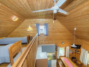 A cozy attic bedroom with a bunk bed, a desk, a small kitchenette, and a ceiling fan. - Kissankello by Interhome (Juuka)