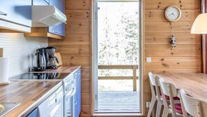 Una cocina moderna con paredes de madera, una estufa integrada y un ventanal con vistas a una terraza.