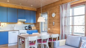Una cocina moderna con armarios azules, techo de madera y un comedor con mesa y sillas.