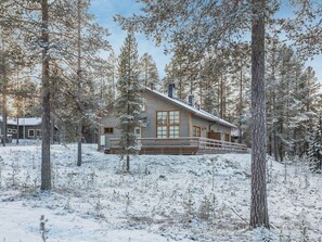 A cabin with a wooden exterior, large windows, and a deck.