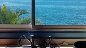 Finestra amb vista a l'oceà i una pica de cuina.