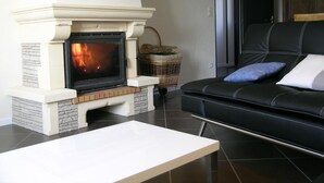 Un salon avec une cheminée, un canapé en cuir noir et une table basse blanche.