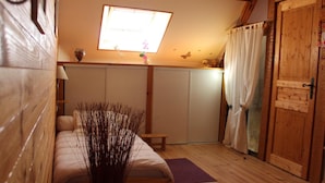 Una habitación acogedora con una cama, una mesita, un ventanal con cortinas y una puerta de madera.