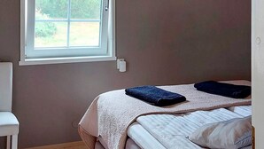 A bedroom with a bed, a window, and a chair. - Villa blomvik by Interhome (Porvoo)