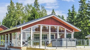 A modern building with a glass facade, a red roof, and a wooden deck area. - Villa blomvik by Interhome (Porvoo)