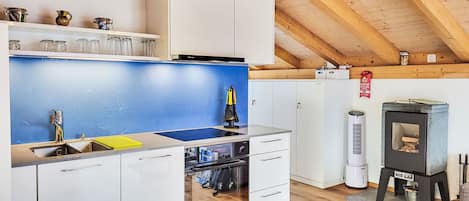 A modern kitchen with white cabinets, a blue backsplash, and a wooden ceiling.