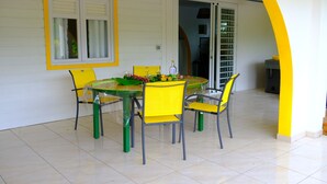 A dining area with a table and four chairs, a bottle of champagne, and a vase with flowers.