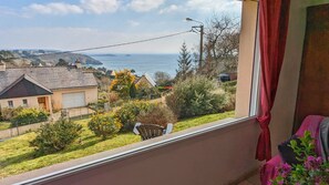 Varanda com vista para uma área residencial, uma cadeira e uma cortina vermelha.