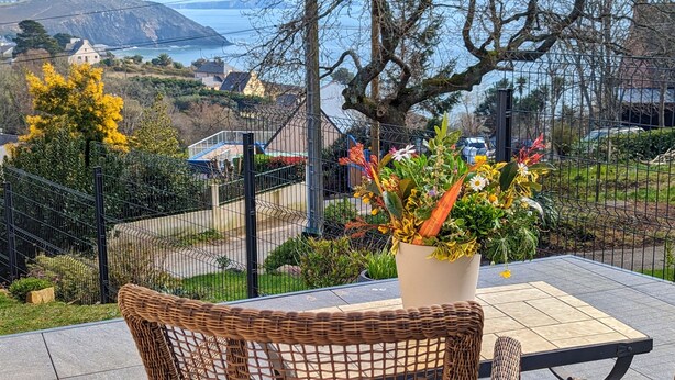 A patio with wicker furniture, a potted plant, and a view of a coastal landscape. - House with panoramic sea view and dream beach at 500 m (Crozon)