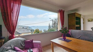 A cozy living room with a large window, a wooden table, and a sofa. - House with panoramic sea view and dream beach at 500 m (Crozon)