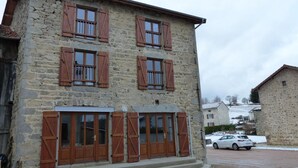 Un bâtiment en pierre avec des volets en bois et une voiture garée devant.