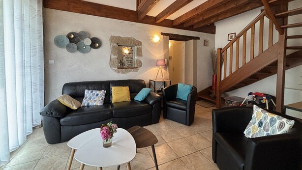 Ein Wohnzimmer mit einem schwarzen Ledersofa, einem weißen Couchtisch und einer Treppe mit Holzwangen.