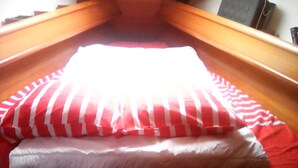 A bed with a red and white striped pillow and a white pillow. - Stays and unusual nights at the port of Morlaix on a 12-meter sailboat (Morlaix)