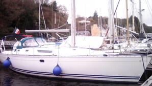 A white boat docked at a marina with blue buoys and other boats in the background. - Stays and unusual nights at the port of Morlaix on a 12-meter sailboat (Morlaix)