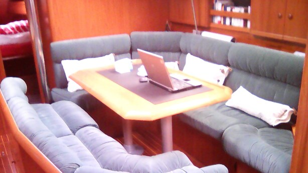 A cozy seating area with a laptop on a table, surrounded by cushioned seating. - Stays and unusual nights at the port of Morlaix on a 12-meter sailboat (Morlaix)